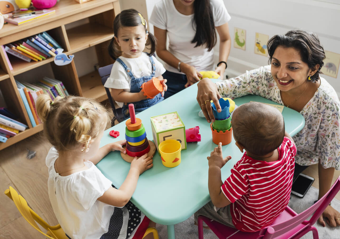 A woman playing with some small children on the table